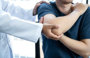 A doctor examining a patient with a shoulder injury.